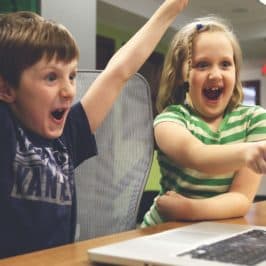 Boy and girl looking excitedly at a laptop