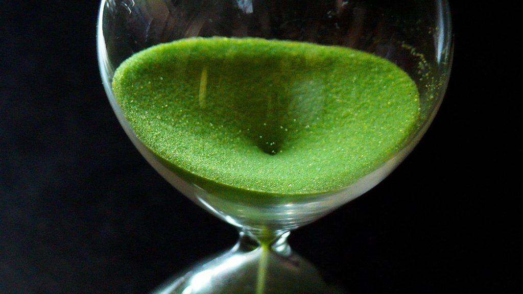 Green sand filtering through an hourglass