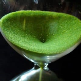 Green sand filtering through an hourglass