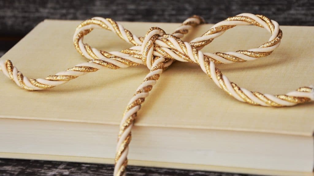Hardback cream-covered book with a gold rope bow