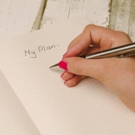 Handing holding pen over a notebook with words 'My Plan'