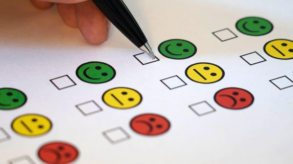 Pen hovering over feedback form with happy, indifferent and sad emojis