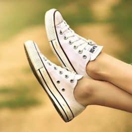 Feet wearing white Converse shoes