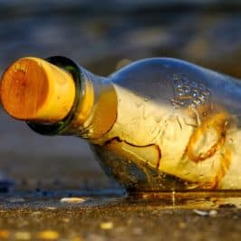 Stoppered bottle on shoreline with scrolled paper inside